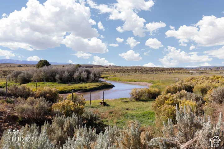 Natural creek meandering through expansive acreage featuring native desert vegetation and distant mountain silhouettes