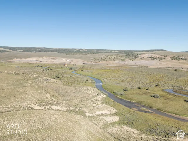 Expansive acreage featuring a winding creek, natural vegetation, rolling terrain, and distant mountain topography