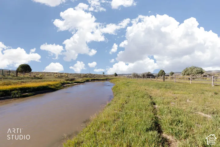 Waterfront property featuring a natural creek, expansive meadow, and split-rail perimeter fencing