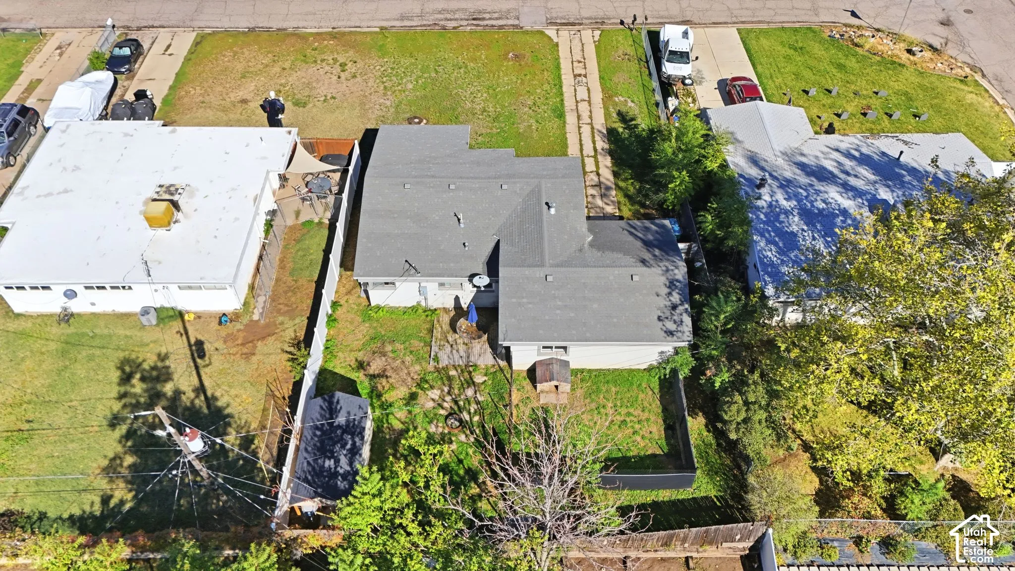 Aerial perspective of a detached property featuring a fenced backyard, mature landscaping, and a driveway with concrete paved paths