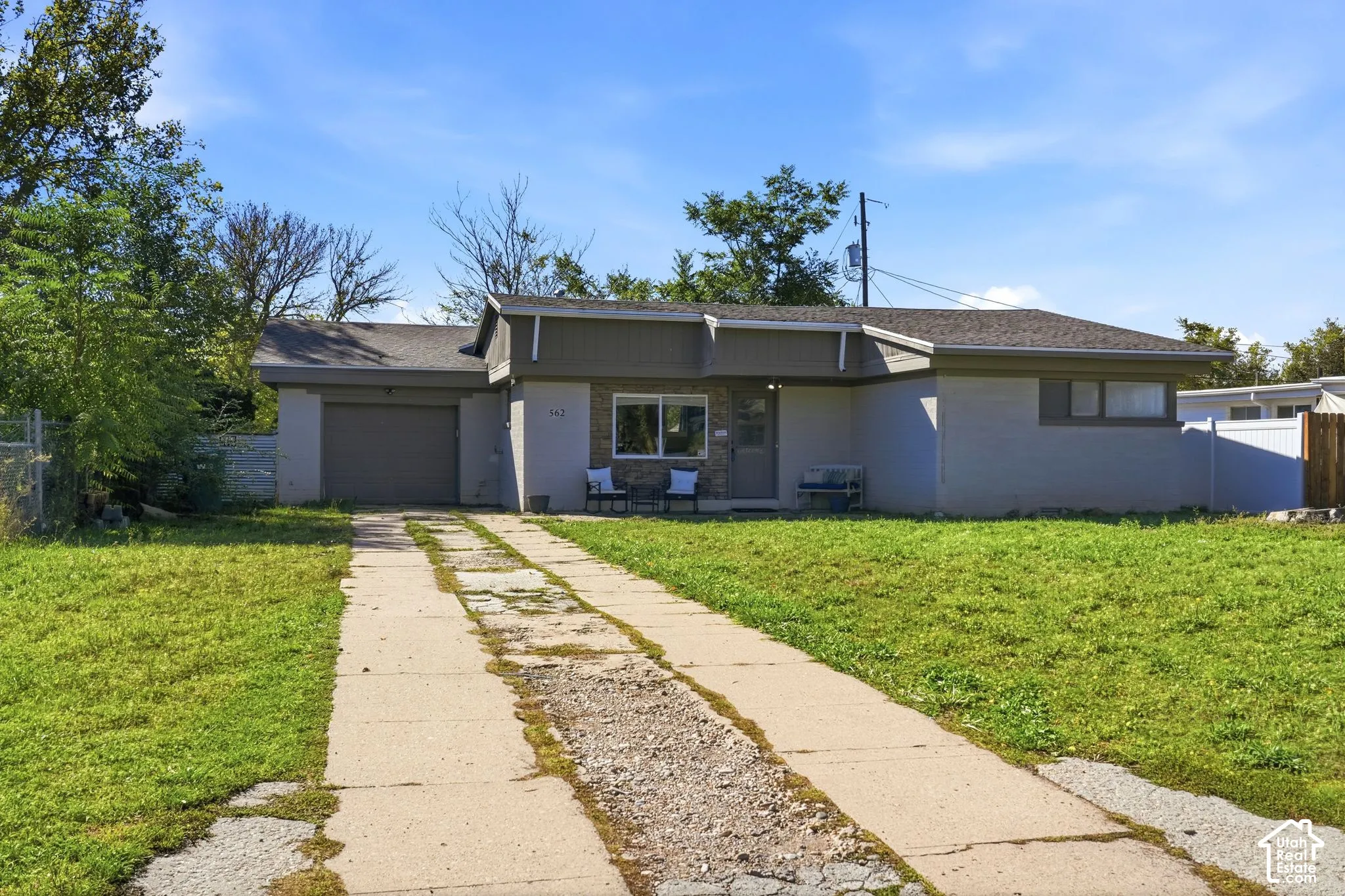 Single-story residence featuring a painted masonry exterior, stone-veneer entryway, attached garage, and asphalt shingle roof