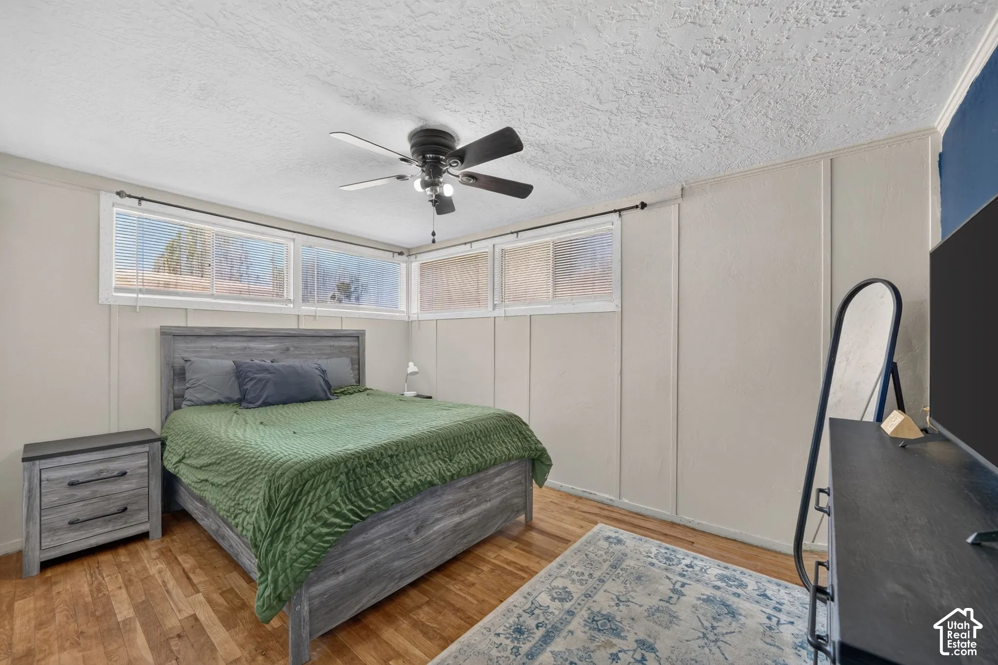 Room featuring wood-finish flooring, paneled walls, and a ceiling fan with integrated lighting
