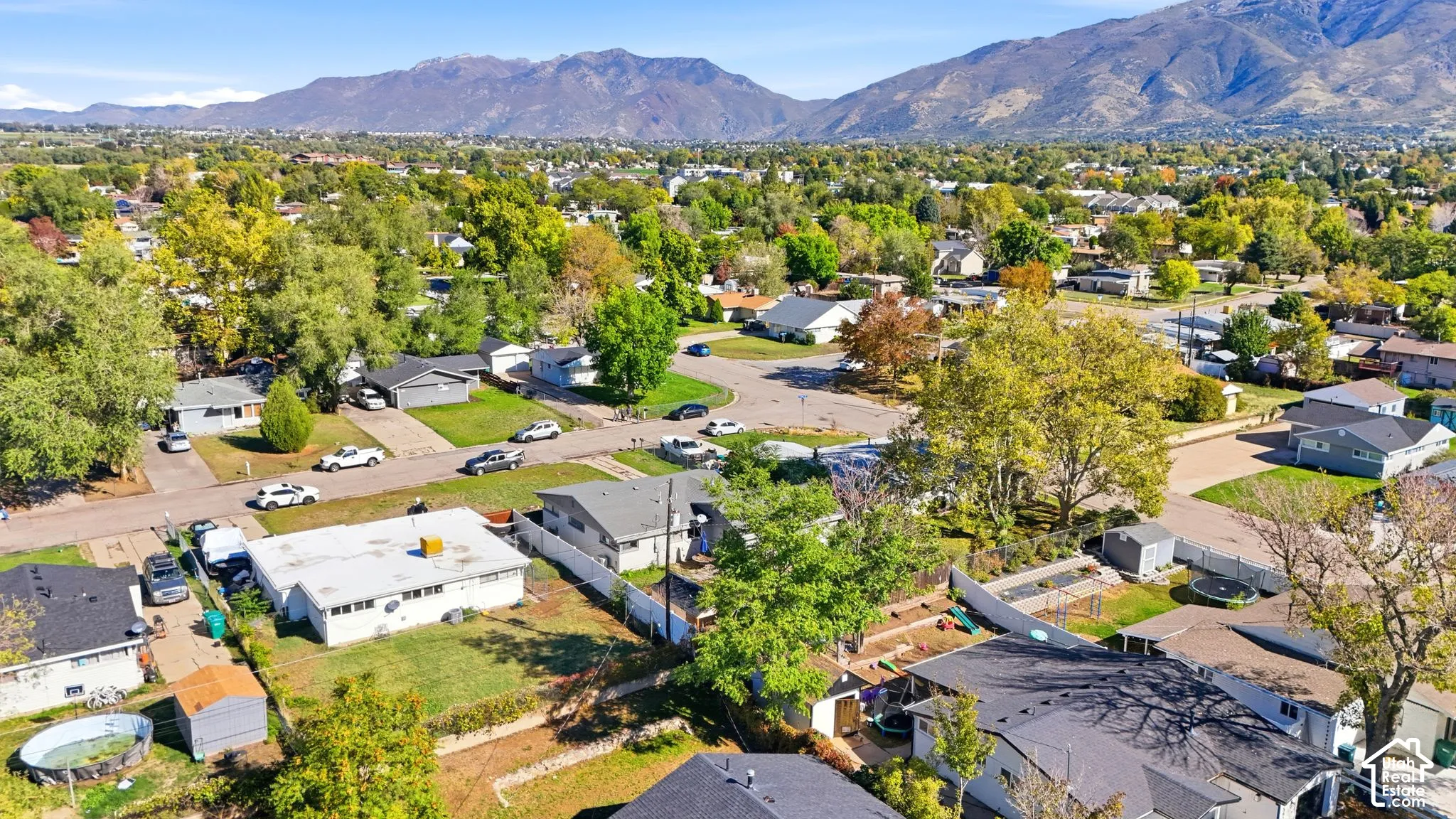 Aerial perspective of the residential area featuring mature trees, established landscaping, and a mountain range backdrop