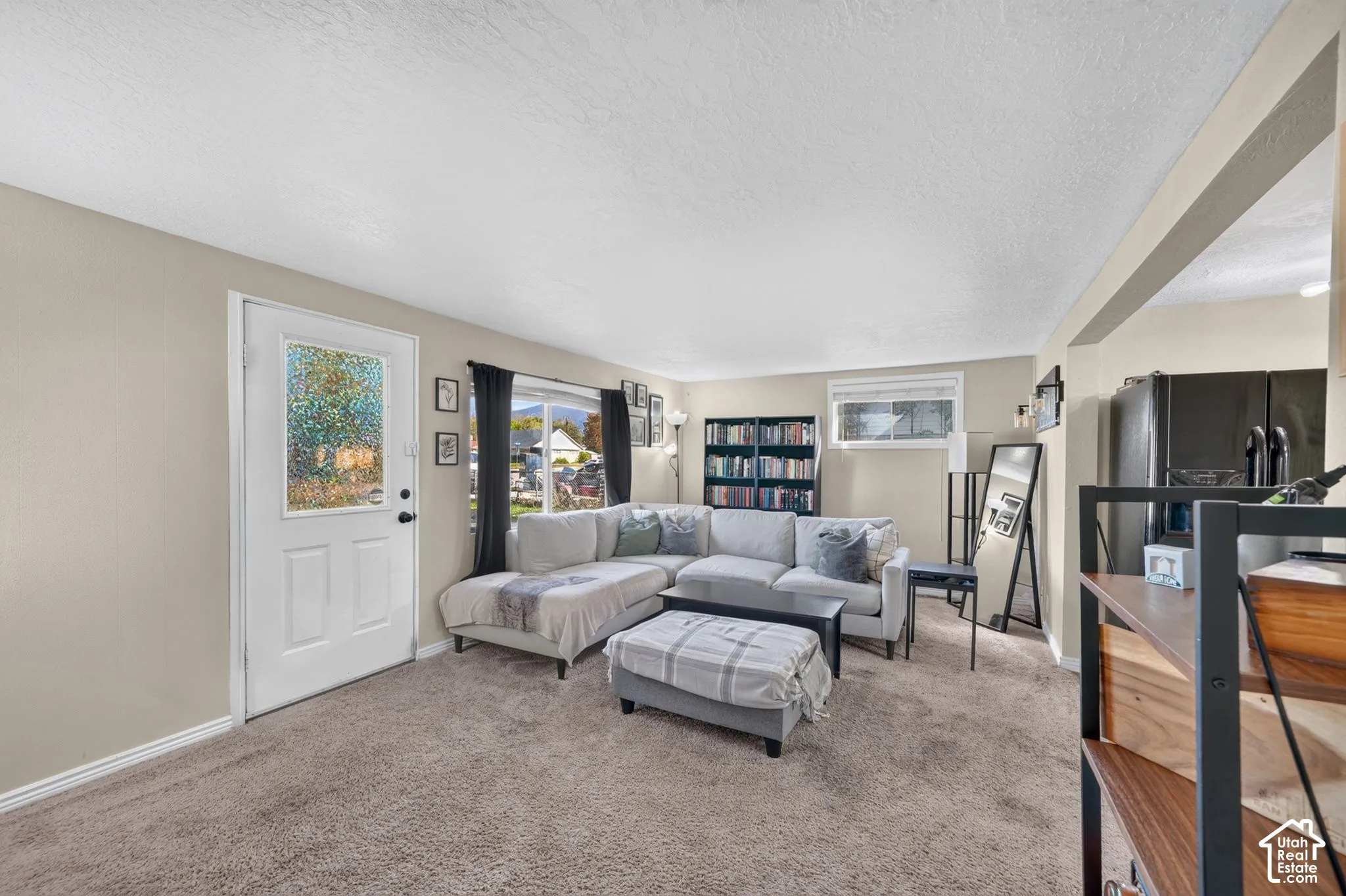 Living area featuring neutral wall paint, textured ceiling, carpeted flooring, and a glass-paneled exterior door