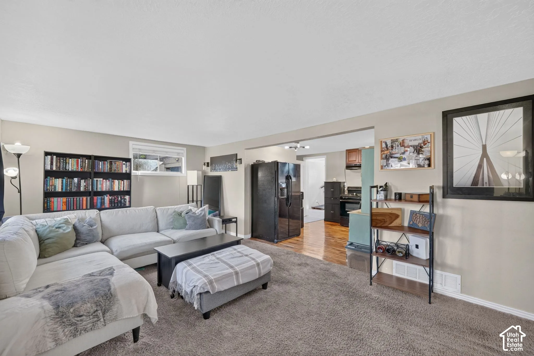 Open-concept living space featuring neutral wall paint, wall-to-wall carpeting, and wood-finish flooring in the kitchen area