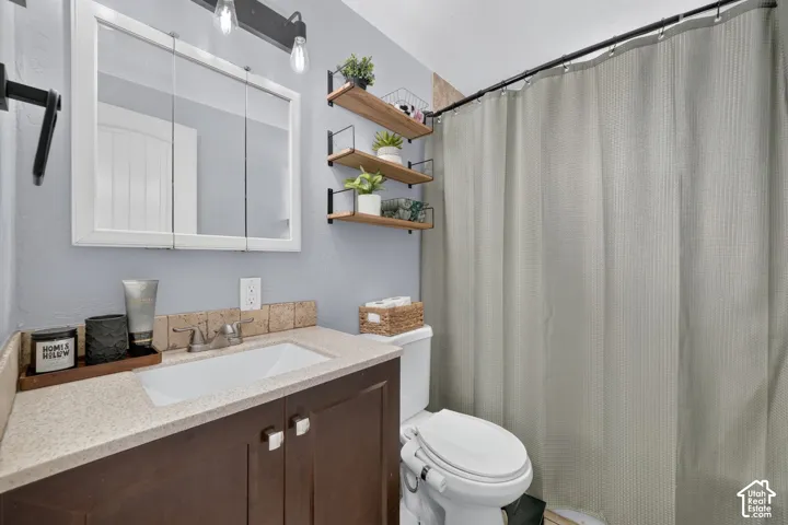 Vanity cabinet with a solid surface countertop, integrated rectangular sink, wall-mounted three-tier shelving system, tri-fold medicine cabinet, and industrial-style vanity lighting