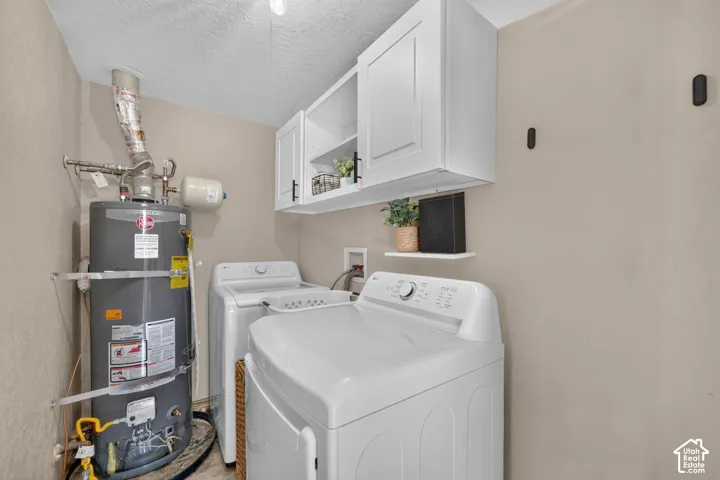 Laundry space featuring white shaker-style wall cabinets with matte black hardware and a built-in wall-mounted shelf