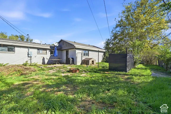 Exterior featuring light-colored painted brick siding, a concrete paver patio, and a chain-link fenced perimeter