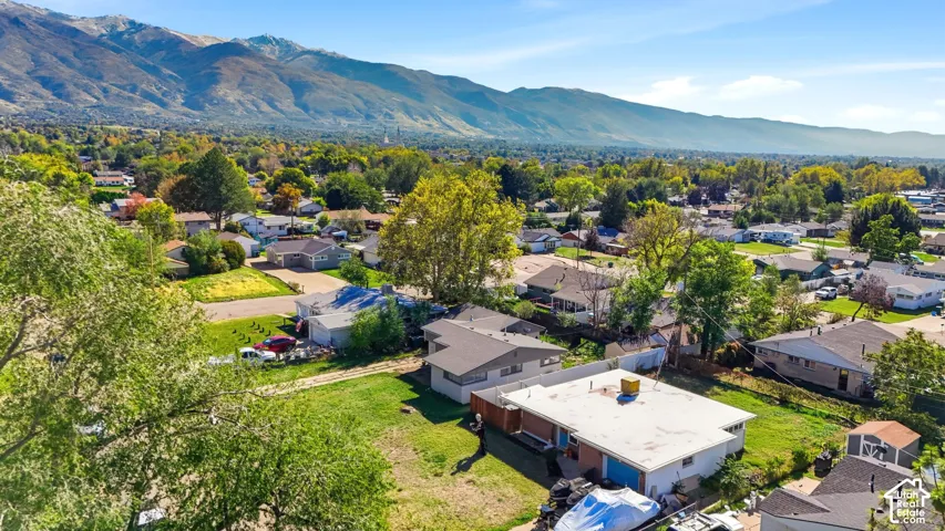 Aerial perspective featuring a single-story residence with a multi-section roof, brick exterior accents, and a dedicated attached garage, all set against a prominent mountain backdrop