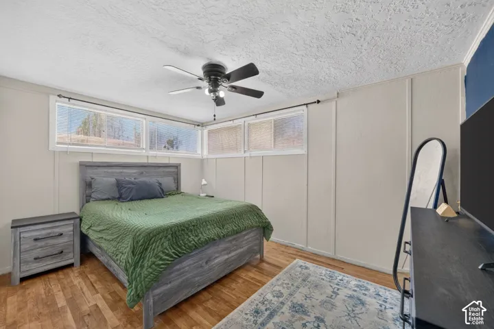 Room featuring wood-finish flooring, paneled walls, and a ceiling fan with integrated lighting