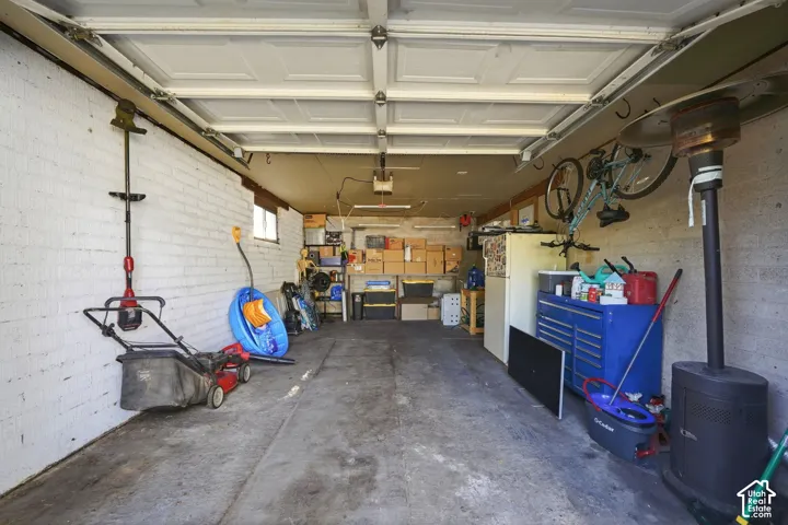Attached garage featuring painted masonry walls, concrete flooring, an automated overhead door opener, and a single pane window