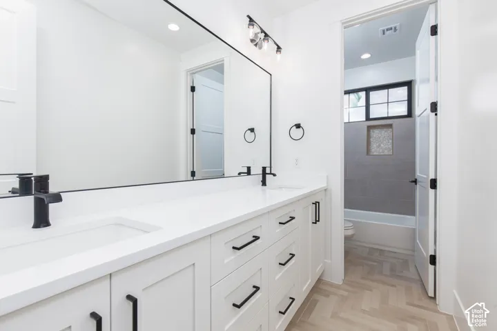 Double vanity with integrated white rectangular sinks, quartz countertop, matte black fixtures, and herringbone-patterned flooring