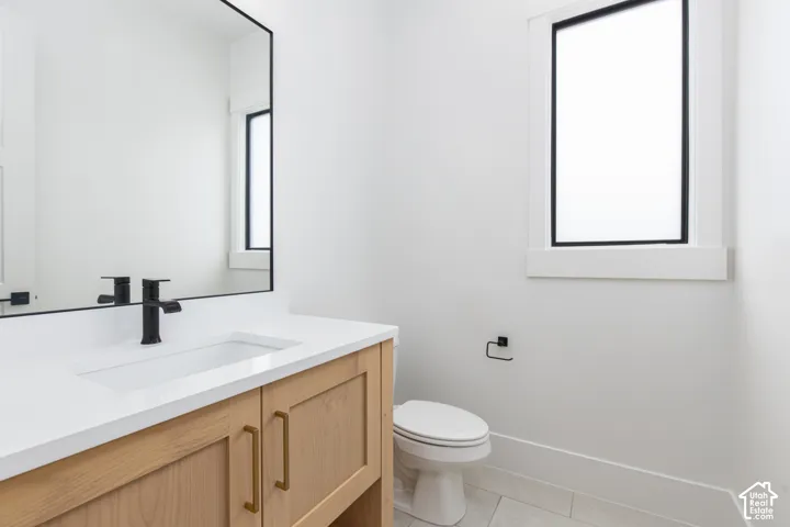 Wood-finish vanity with a rectangular sink, quartz countertop, matte black faucet, and frameless mirror