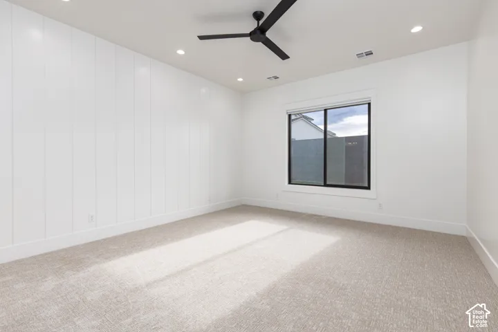 Interior space featuring vertical board-and-batten wall detailing, neutral carpeting, recessed lighting, and a matte black ceiling fan