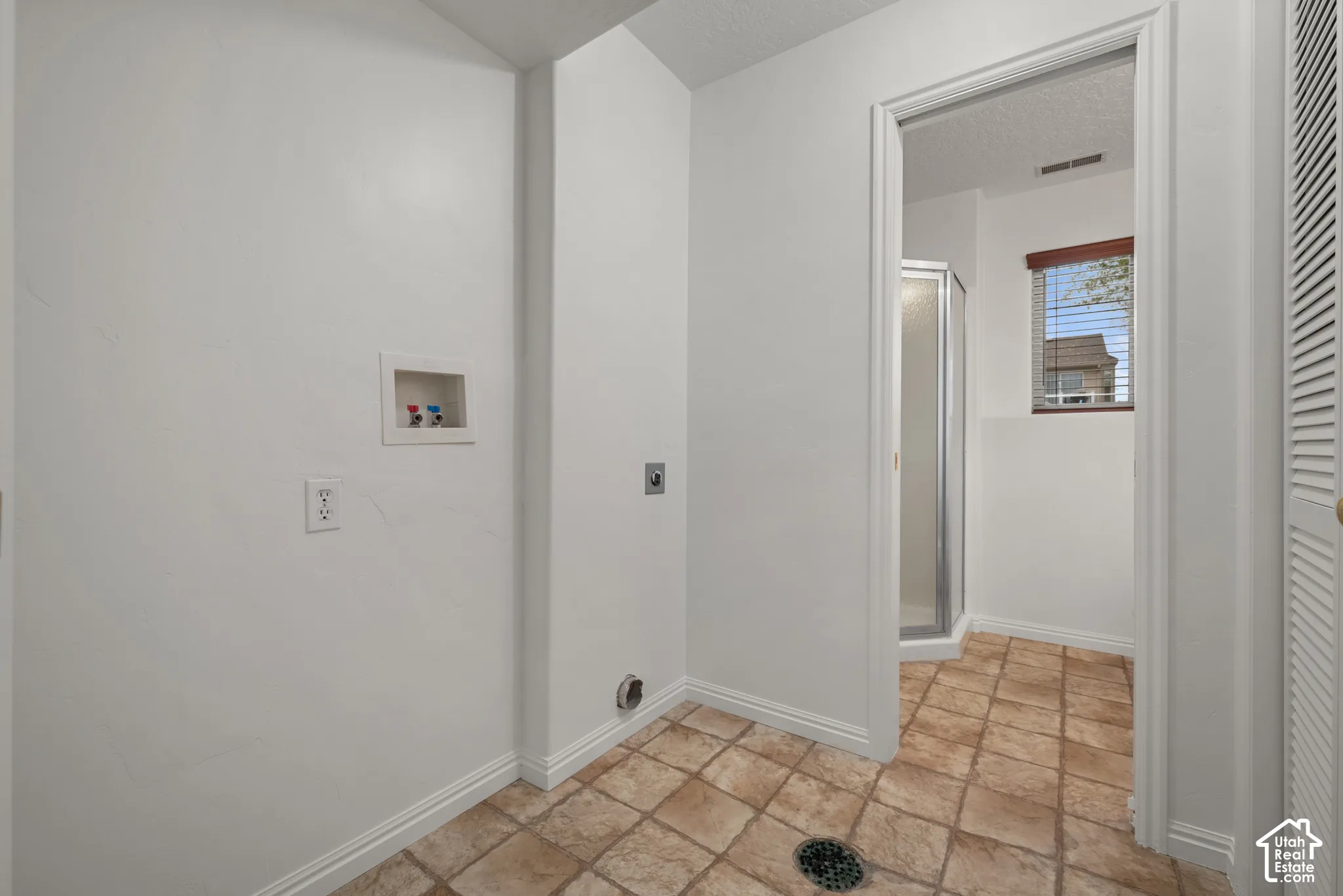 Utility area featuring tile flooring, dedicated washer and dryer hookups, floor drain, and louvered closet doors