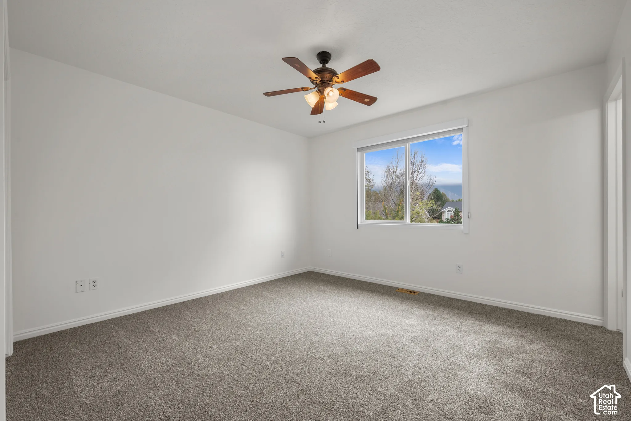 Neutral-toned carpeting, ceiling fan with integrated lighting, sliding window, and exterior mountain scenery
