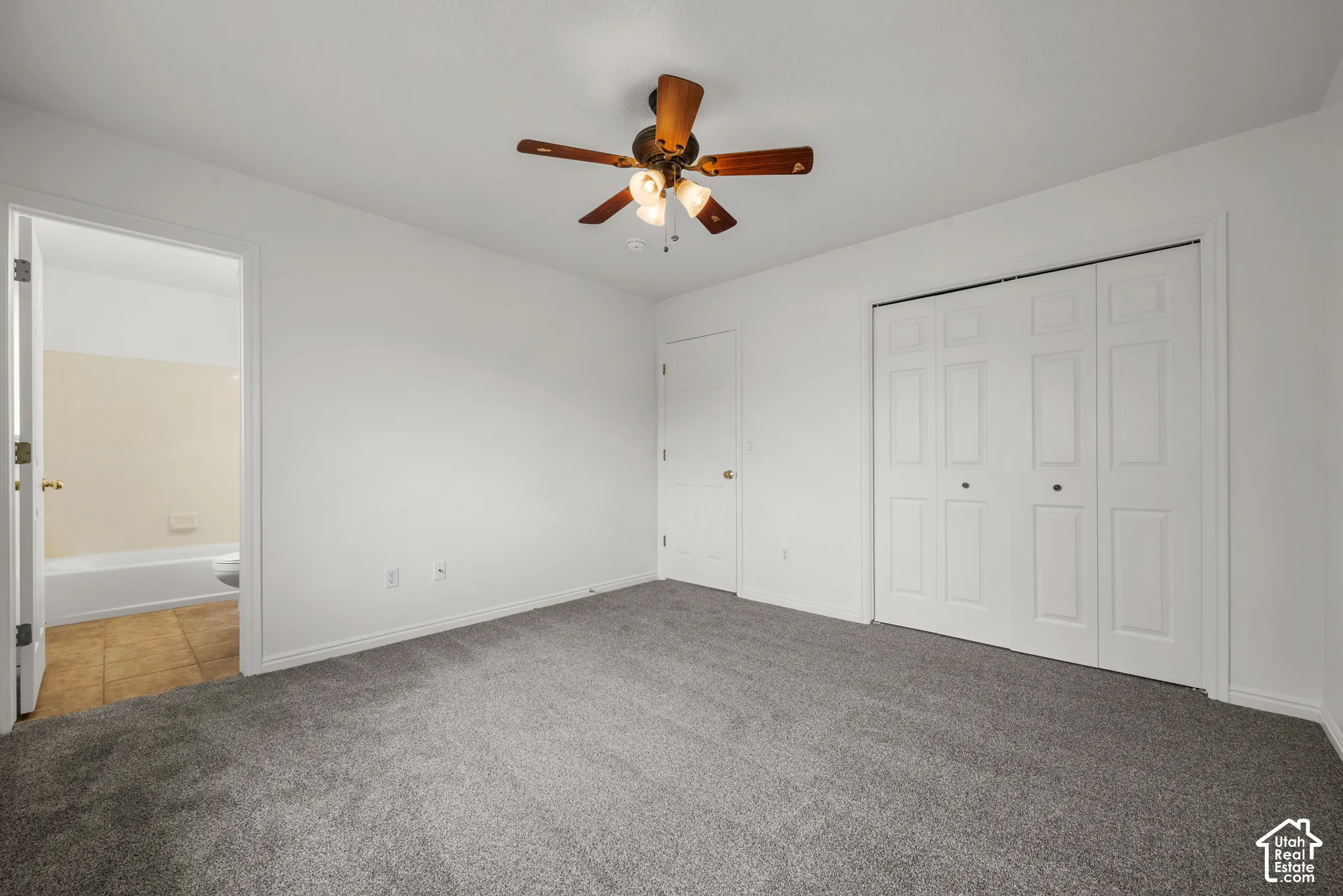 Neutral-toned carpeting, ceiling-mounted fan with integrated light fixture, and bifold closet doors with a multi-panel design