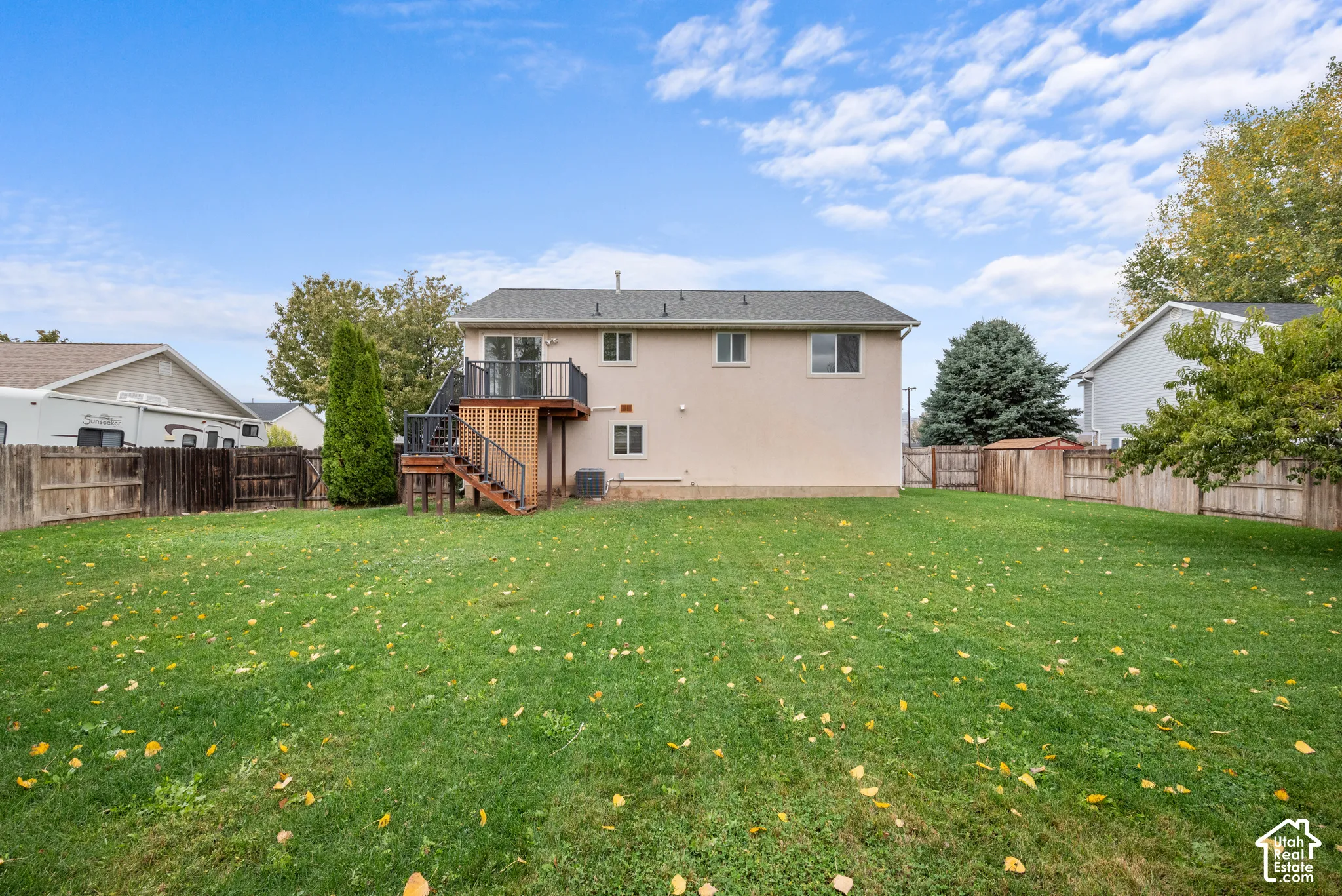 Expansive backyard featuring a level lawn, full wood fencing, and an elevated deck with black metal railing