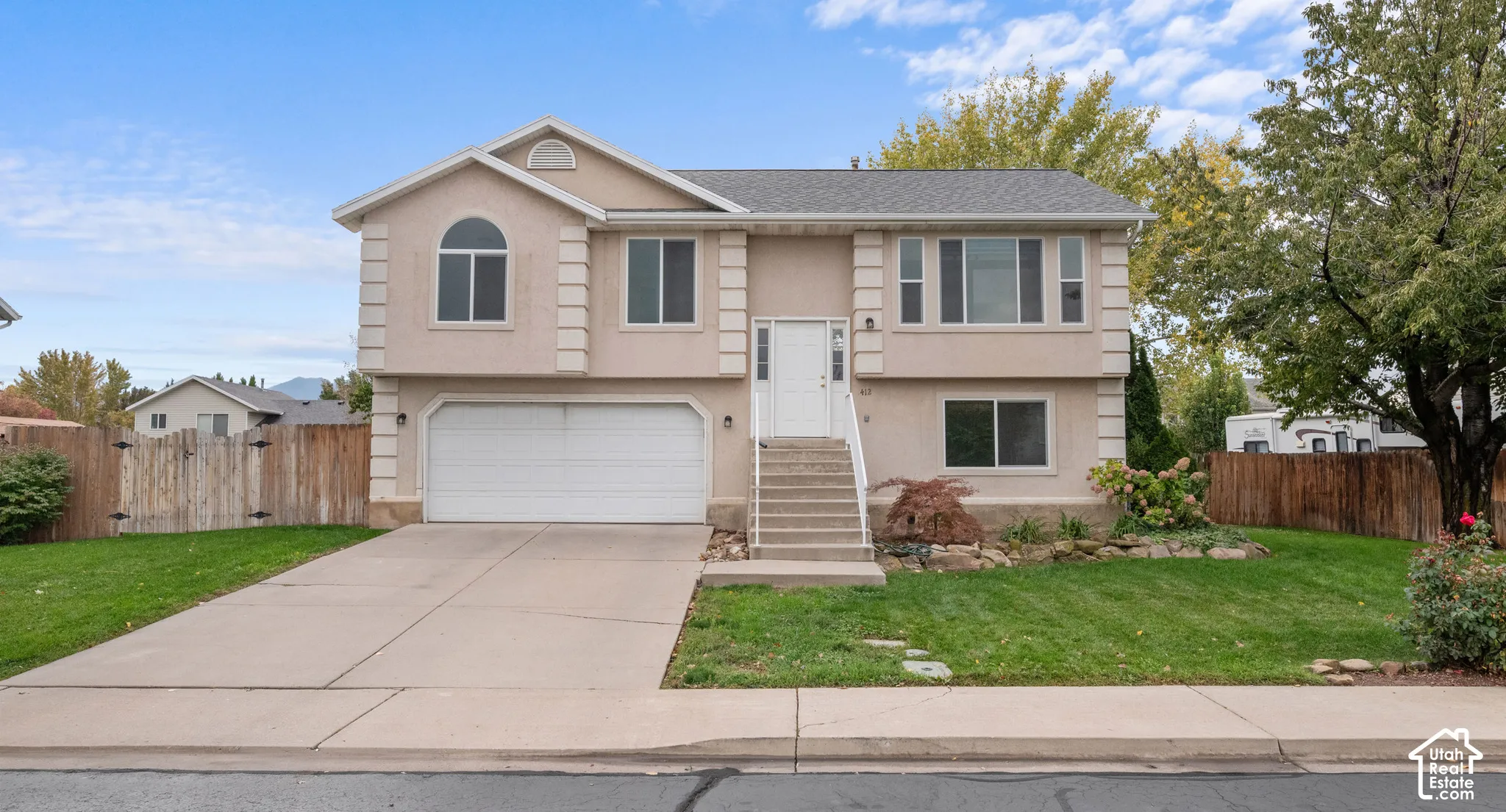 Two-story exterior featuring a stucco facade, quoined corner detailing, an arched transom window, an attached two-car garage, and a concrete driveway