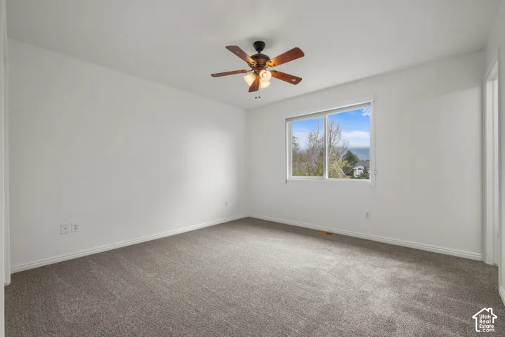 Neutral-toned carpeting, ceiling fan with integrated lighting, sliding window, and exterior mountain scenery
