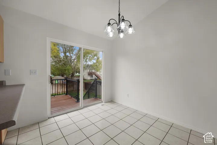 Ceramic tile flooring, five-light iron chandelier, and a sliding glass door providing access to a wood-plank deck with metal railings
