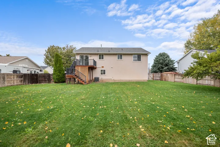 Expansive backyard featuring a level lawn, full wood fencing, and an elevated deck with black metal railing