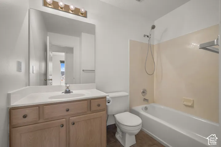 Bathroom featuring a wood-finish vanity with an integrated sink, polished chrome fixtures, a large wall-mounted mirror, and a tub-shower combination with a handheld showerhead
