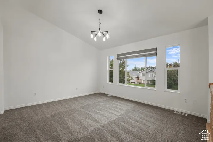 Vaulted ceiling, neutral wall-to-wall carpeting, multi-pane windows, and a multi-arm architectural light fixture