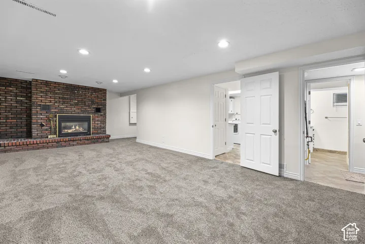 Expansive interior space featuring a floor-to-ceiling brick fireplace with a built-in insert, recessed lighting, neutral carpeting, and multi-panel interior doors