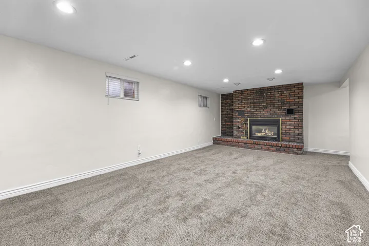 Living area featuring recessed lighting, wall-to-wall carpeting, and a floor-to-ceiling brick fireplace with a raised brick hearth