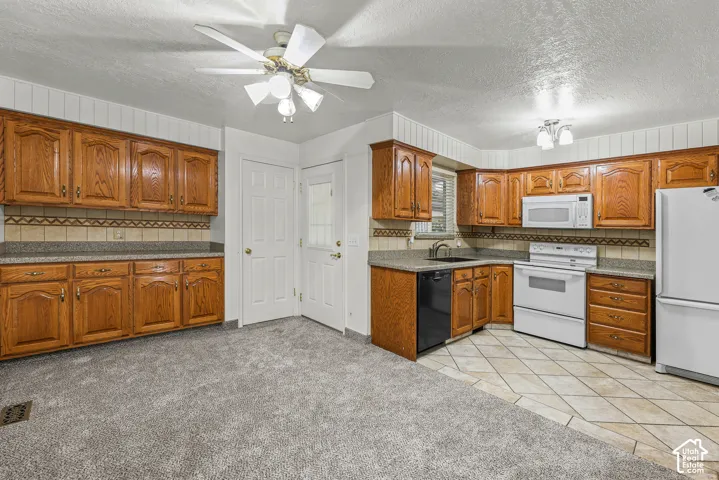 Kitchen featuring medium-tone wood cabinetry, solid-surface countertops with tile backsplash, built-in dishwasher, integrated microwave, and porcelain tile flooring