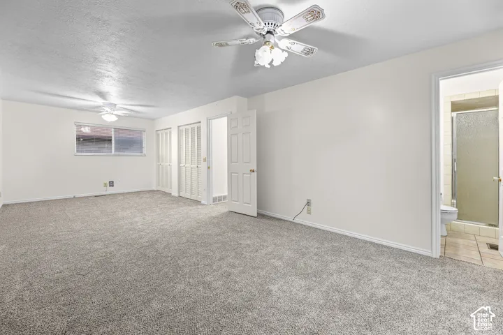 Room featuring neutral carpeting, dual ceiling fans with integrated light fixtures, and white paneled closet doors