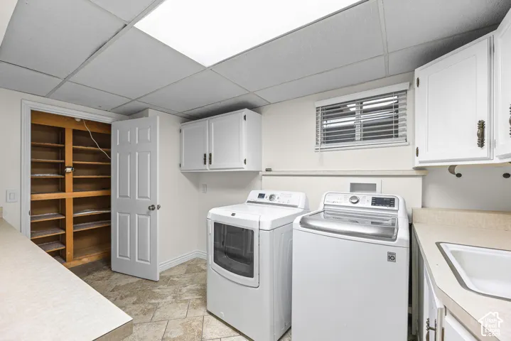Laundry area featuring stone-finish tile flooring, built-in cabinetry, an integrated utility sink with countertop, and an open-shelf storage closet