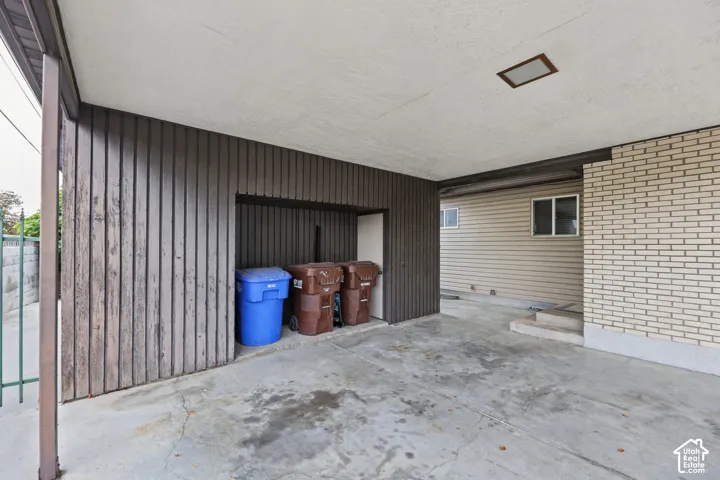 Covered carport featuring vertical wood-finish siding, concrete flooring, and built-in exterior storage