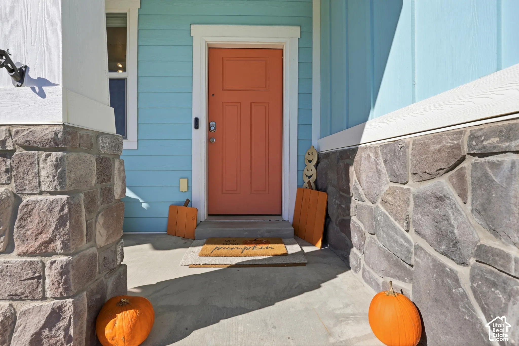 Covered entryway featuring board-and-batten siding, stone-veneer accents, a concrete porch, and a solid-panel door