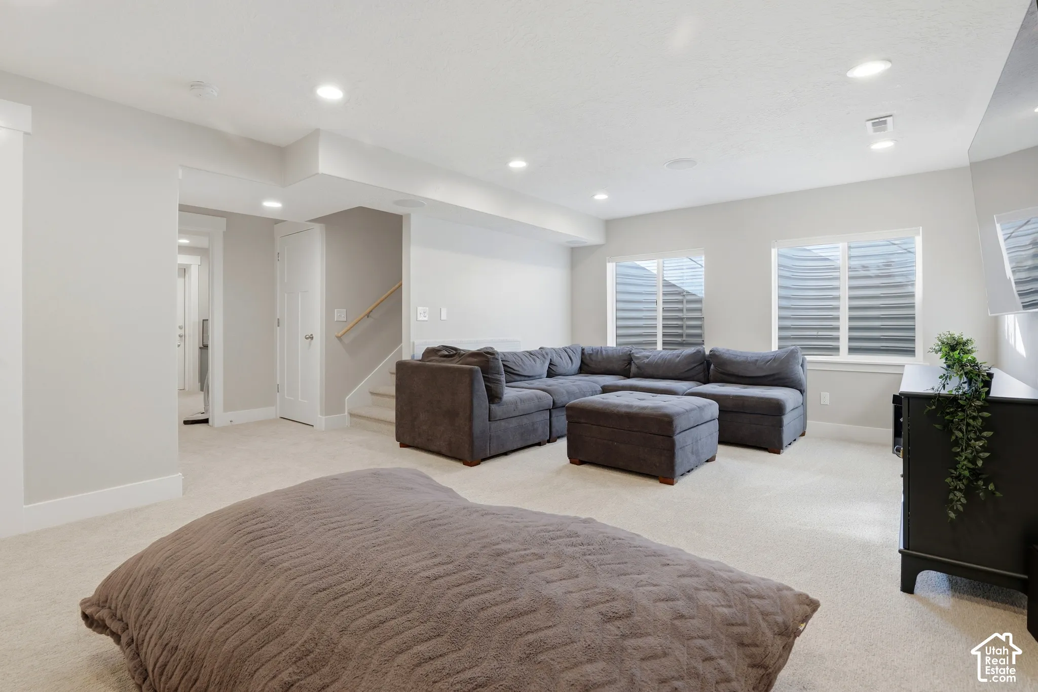 Neutral-toned interior featuring recessed lighting, wall-to-wall carpeting, and double egress windows with window wells
