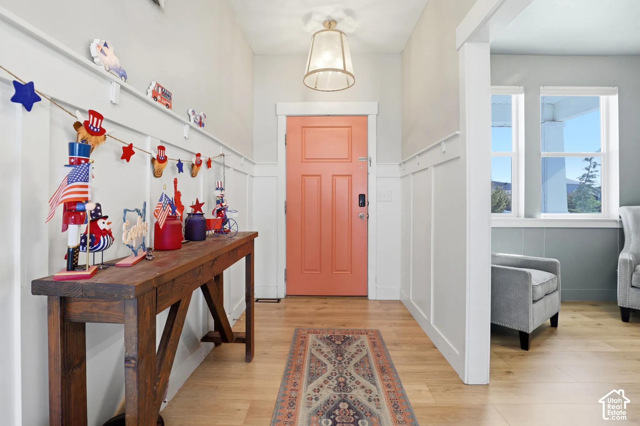 Entryway featuring wood-finish flooring, white board-and-batten wall paneling, and a pendant light fixture