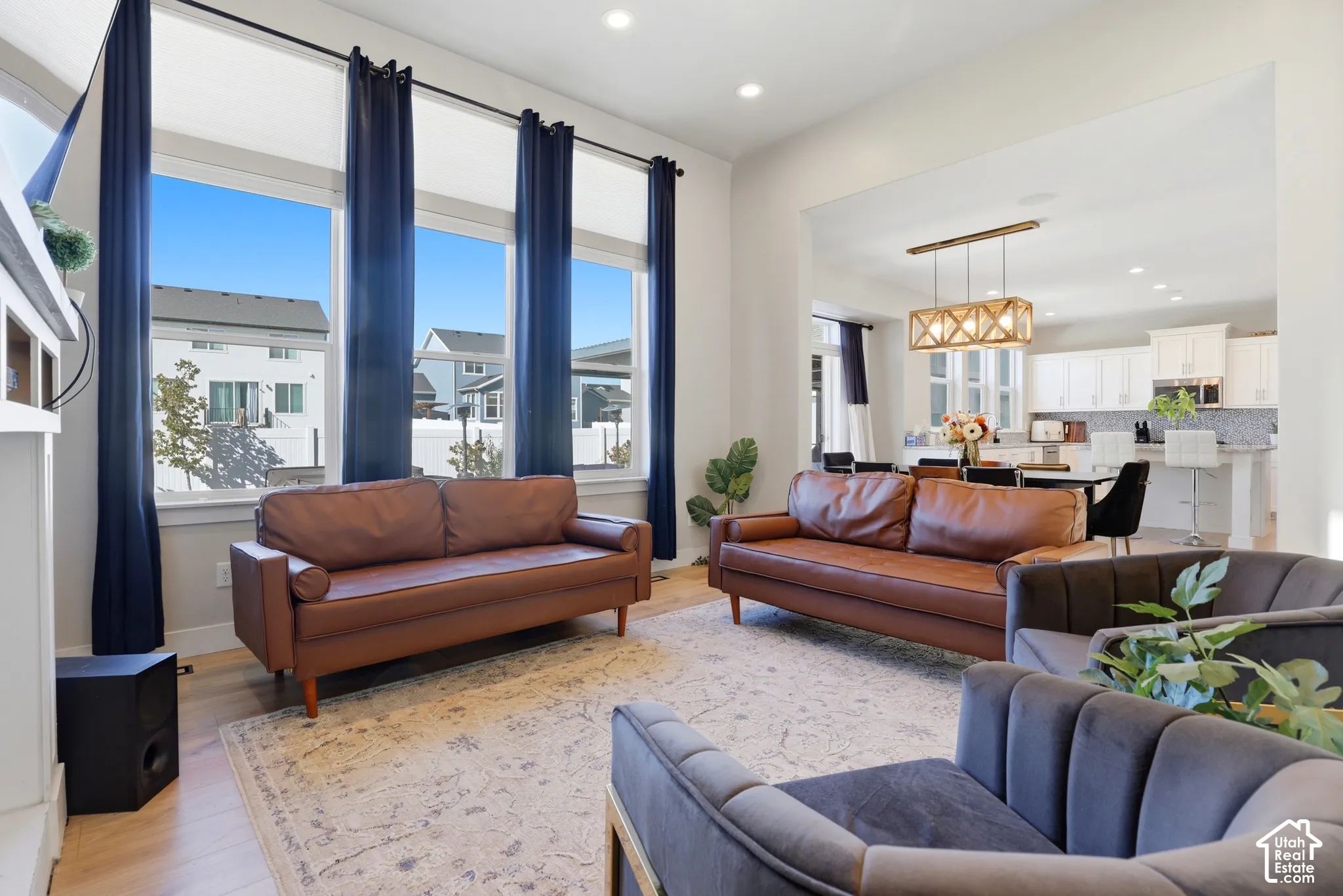 Living area featuring double-height ceilings, floor-to-ceiling windows, recessed lighting, and wood-finish flooring