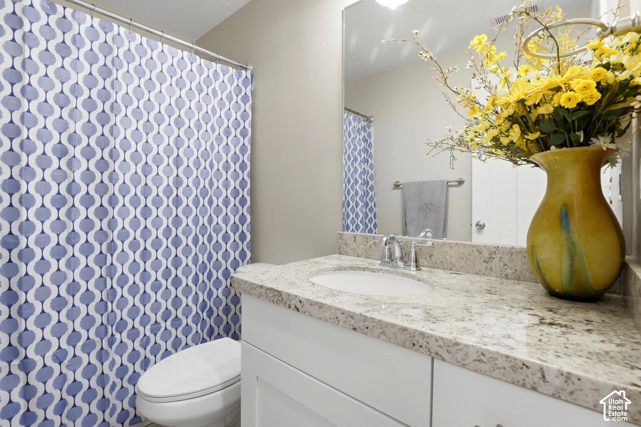 Bathroom featuring a white vanity cabinet, light-toned stone-finish countertop, integrated oval sink, polished chrome faucet, and a large-format vanity mirror