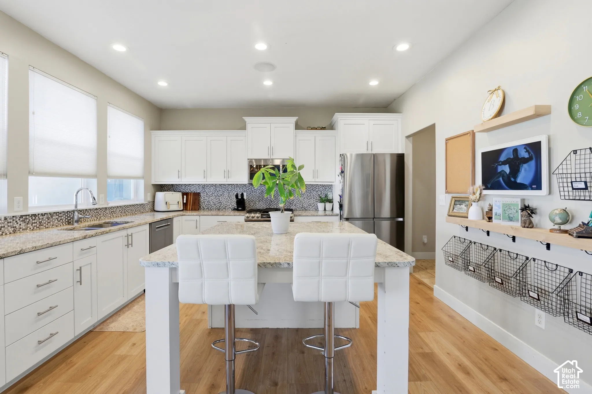 Kitchen featuring white shaker-style cabinetry, stone-finish countertops, decorative tile backsplash, wood-finish flooring, and a central island with integrated seating
