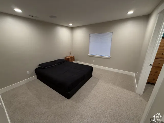 Neutral-toned interior featuring wall-to-wall carpeting, recessed ceiling lighting, and a window with integrated blind
