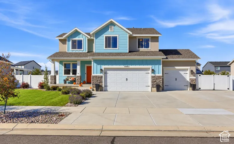 Two-story exterior featuring a mix of horizontal lap siding and vertical board-and-batten siding, stone veneer accents, an asphalt shingle roof, a three-car garage, and concrete driveway