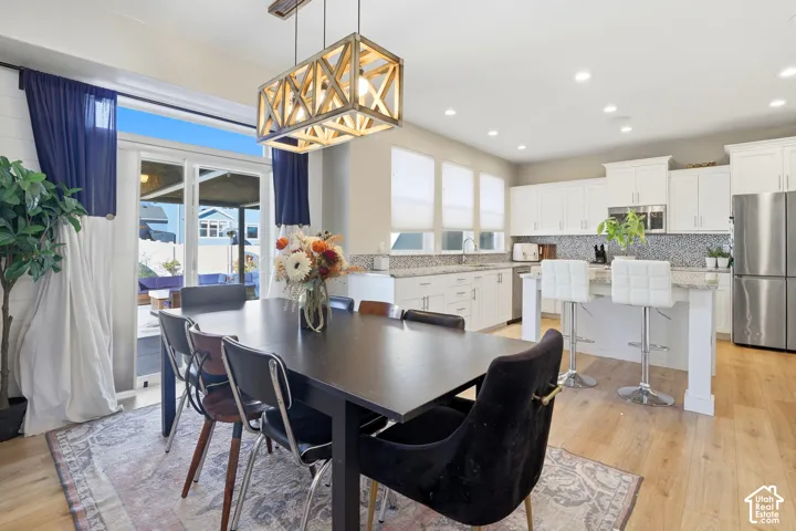 Open-concept space featuring wood-finish flooring, recessed lighting, white cabinetry, a kitchen island with stone-surface countertop, and a geometric wood-frame chandelier