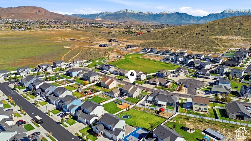 Aerial perspective of a multi-level suburban residence featuring a fenced backyard, asphalt shingle roofing, and a mountain backdrop