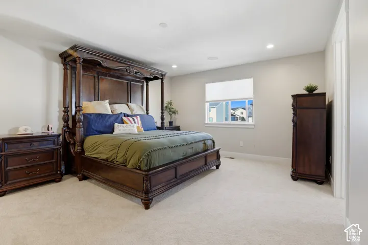 Neutral wall finishes, plush carpeting, recessed lighting, and a window with a roller shade