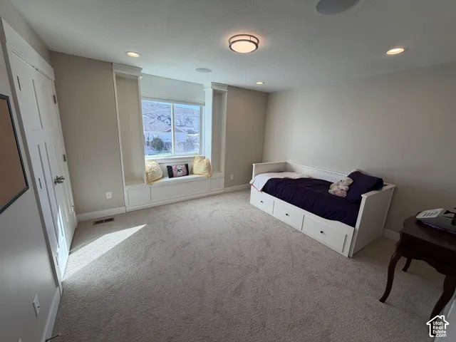 Built-in window seat with integrated shelving, recessed lighting, carpeted flooring, and multi-panel interior door