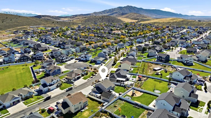 Aerial perspective featuring a residential lot with fenced perimeter, lawn space, and backdrop of mountain topography