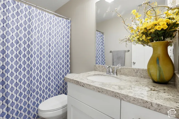 Bathroom featuring a white vanity cabinet, light-toned stone-finish countertop, integrated oval sink, polished chrome faucet, and a large-format vanity mirror
