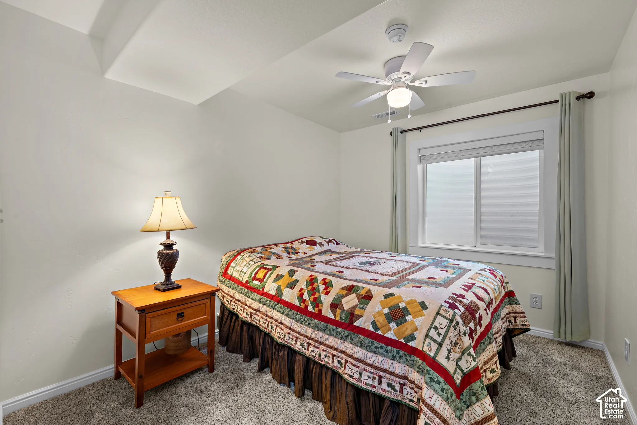 Neutral interior space featuring neutral wall tones, carpeted flooring, a recessed window with white casing, and a ceiling-mounted light fixture with a fan