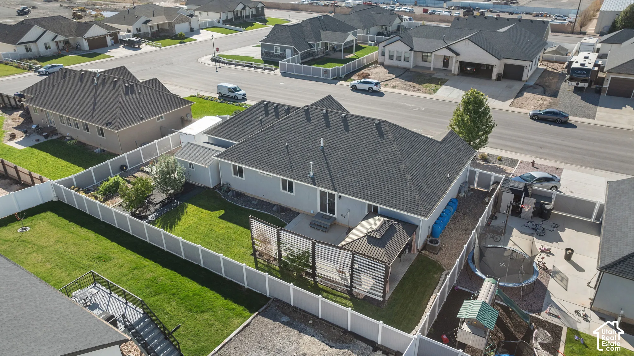 Fenced backyard featuring a manicured lawn, concrete patio, detached metal-roof gazebo, and privacy screening